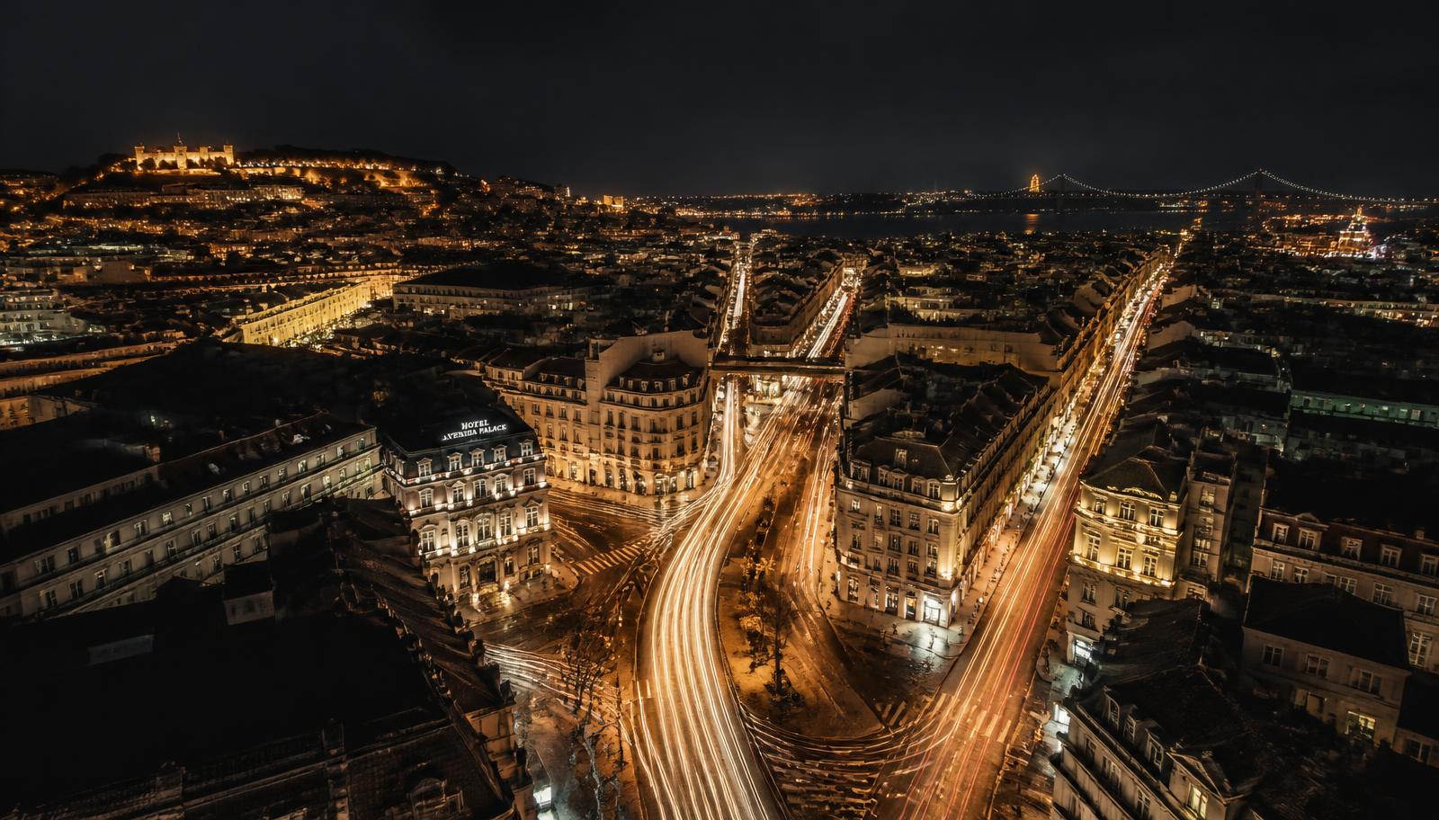 Vista aérea noturna de uma cidade portuguesa com rastos de luz do trânsito